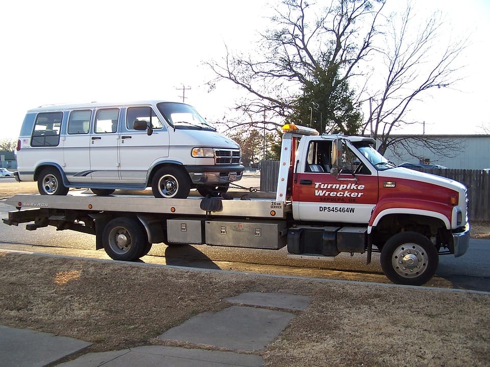 A towing truck carrying a white van